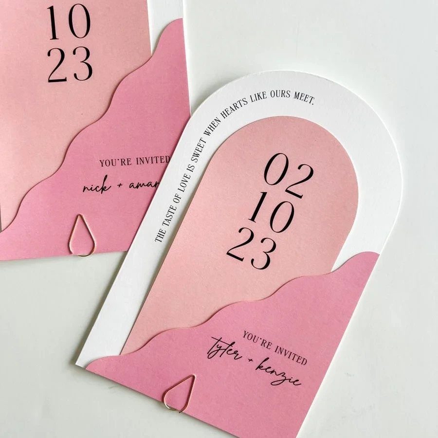 Arched wedding invitations with layered pink paper and clean black typography.