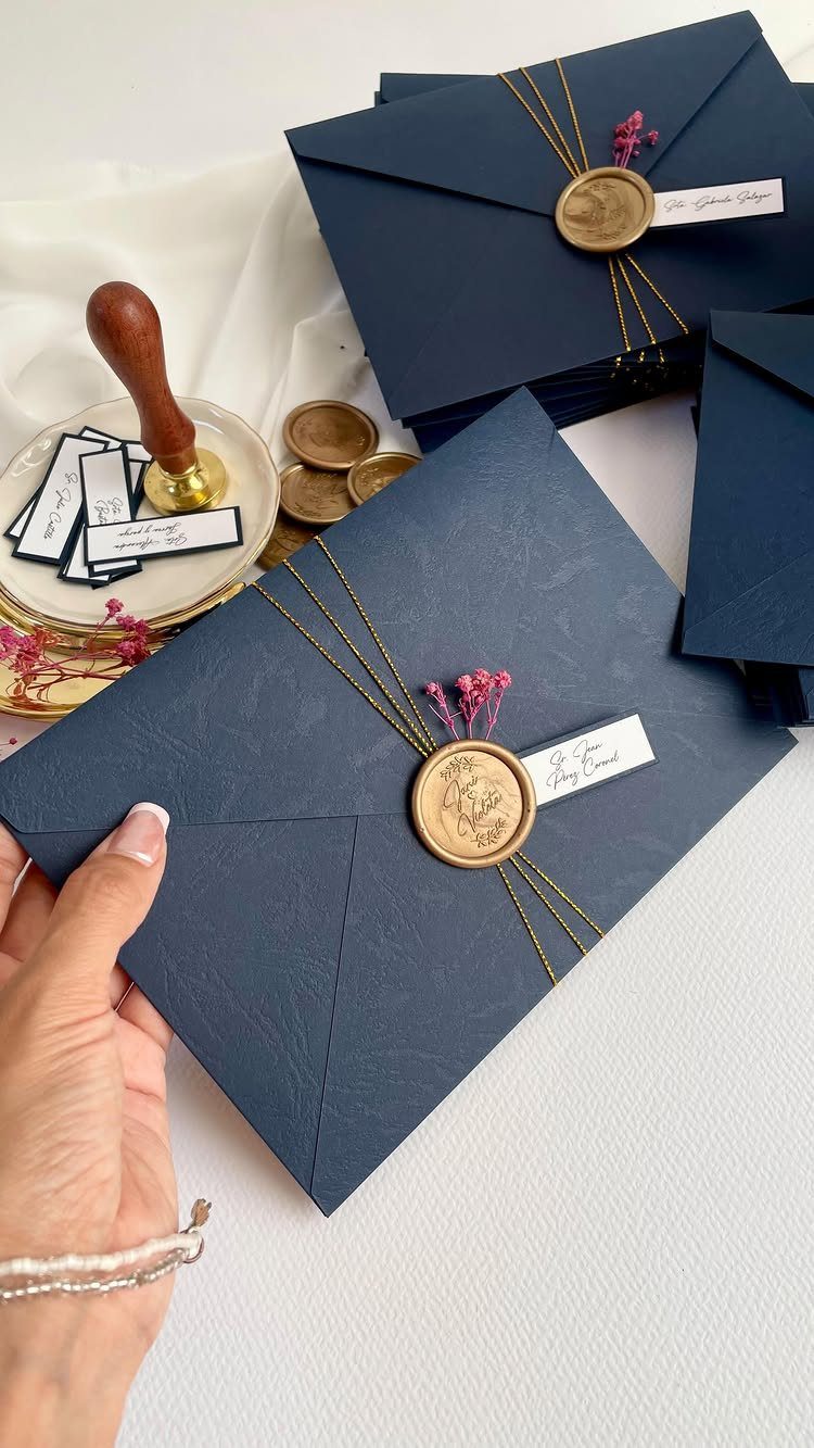 Navy blue envelopes with gold wax seals and pink floral accents on white background