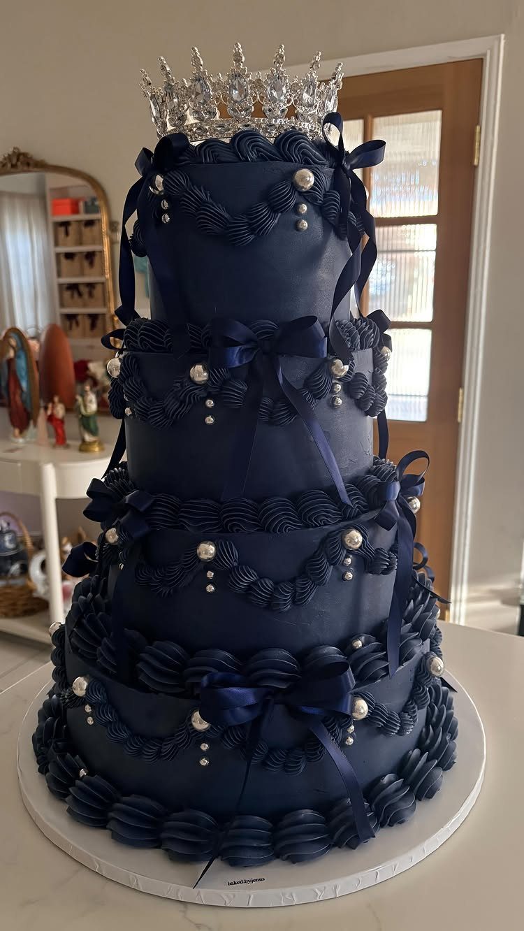 Navy blue tiered wedding cake with silver crown, ribbons, and white pearl accents.