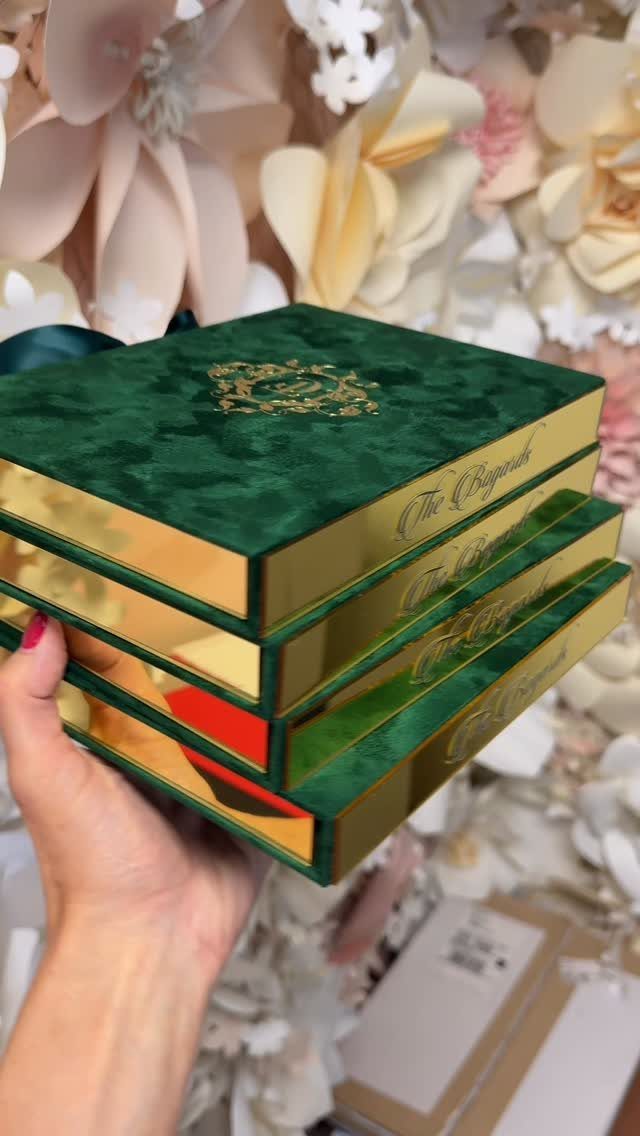 Emerald green velvet boxes with gold metallic edges held against cream flowers