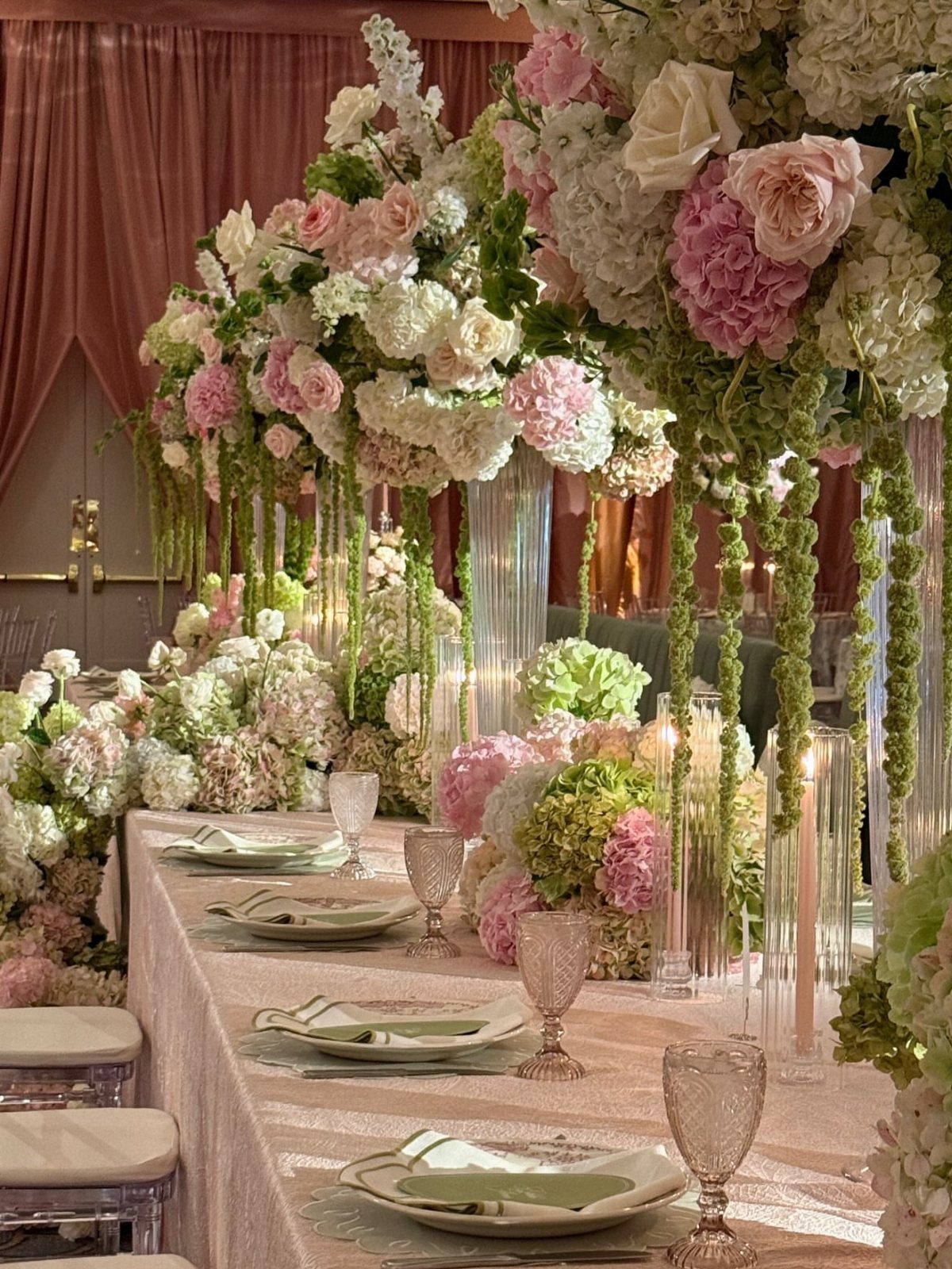 Wedding table with pink linens, sage green plates, and lush pink and green florals.