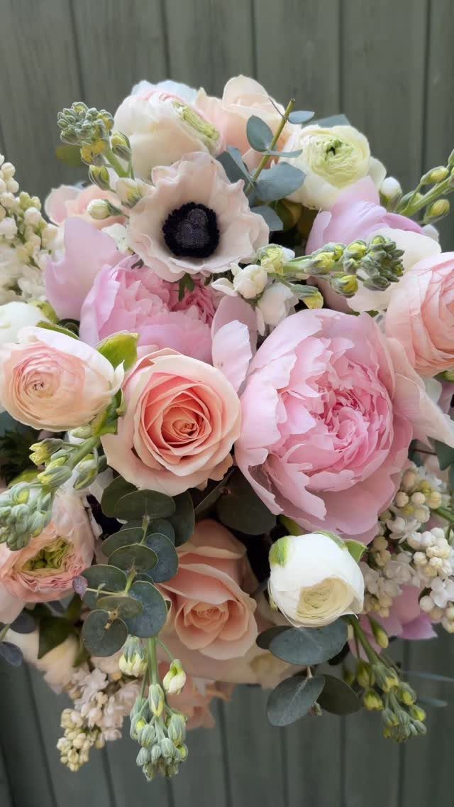 Pink peonies and peach roses in a lush bridal bouquet with eucalyptus leaves.