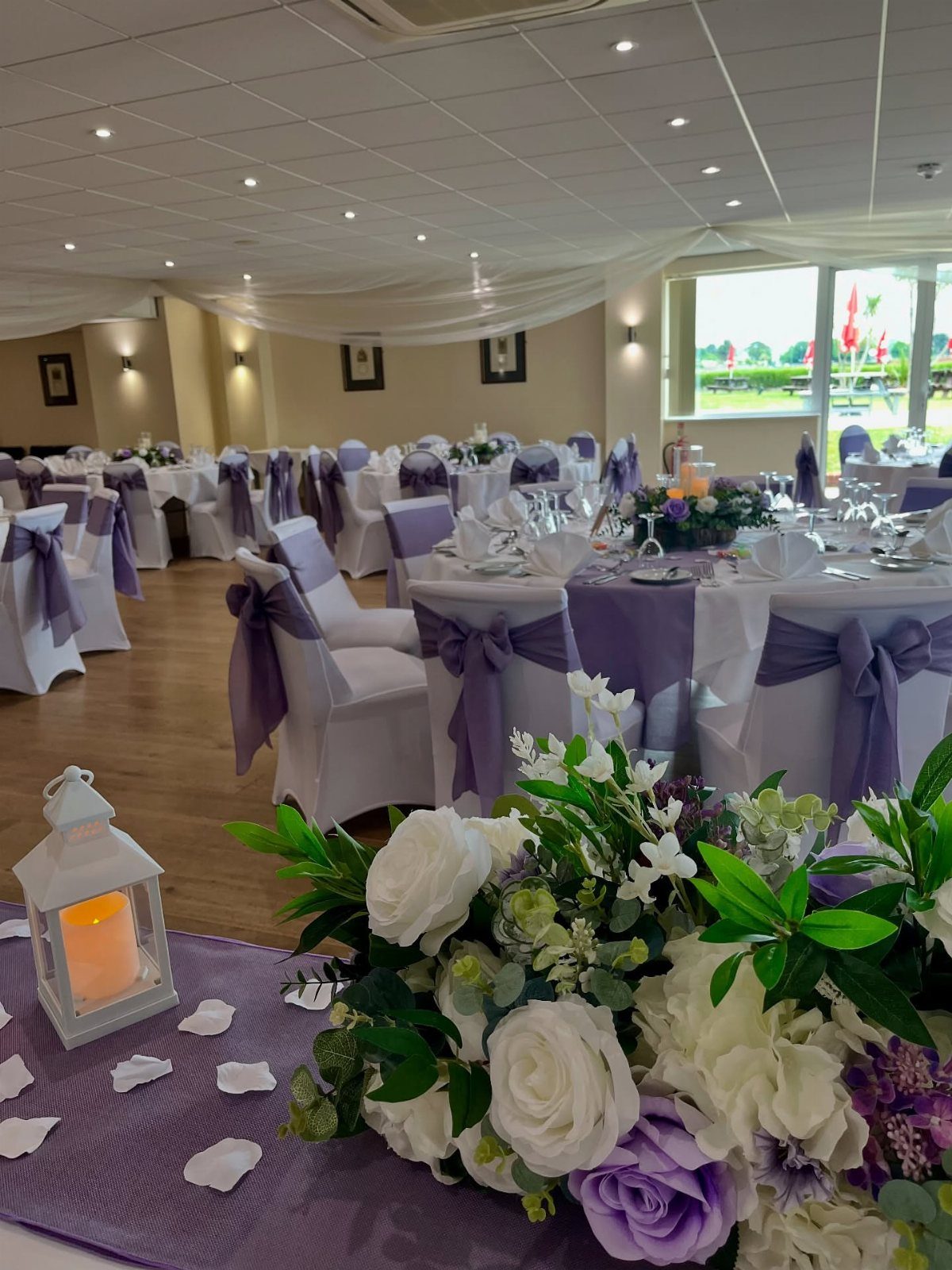 Purple table runners and white floral centerpieces in a wedding reception hall.