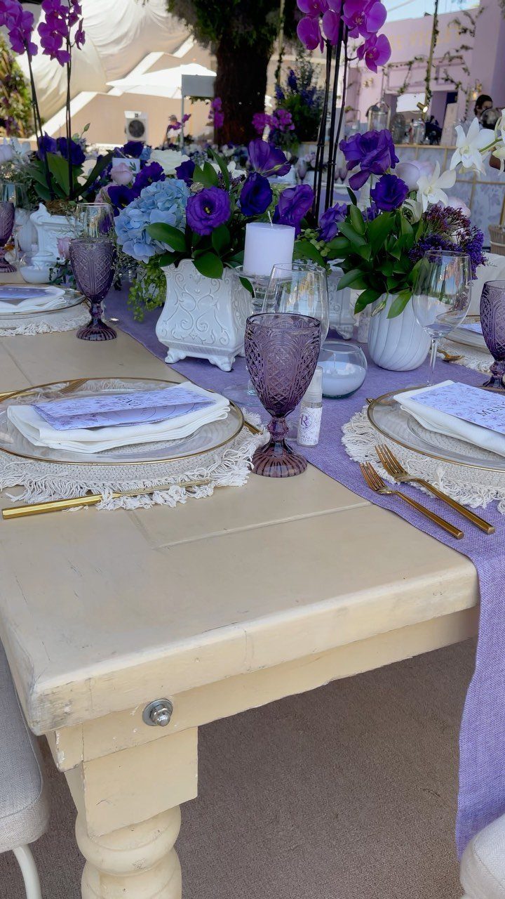 Wedding table setting with purple runner, purple glasses, and purple floral centerpieces.