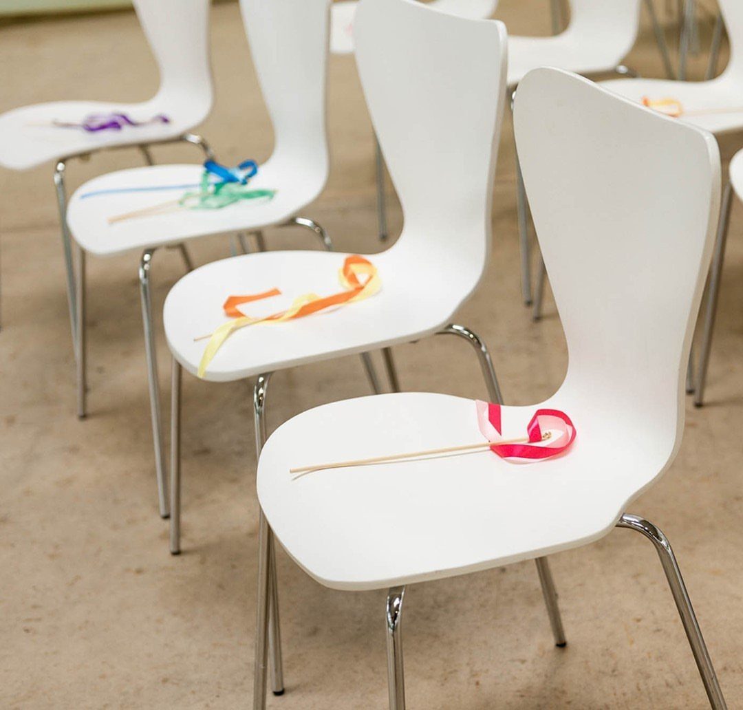 Colorful ribbon wands resting on white chairs for a wedding reception exit.