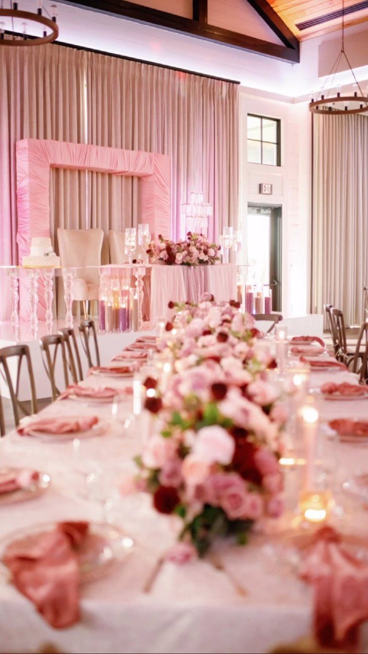 Wedding reception table with pink rose centerpieces and glowing candles in glass vases