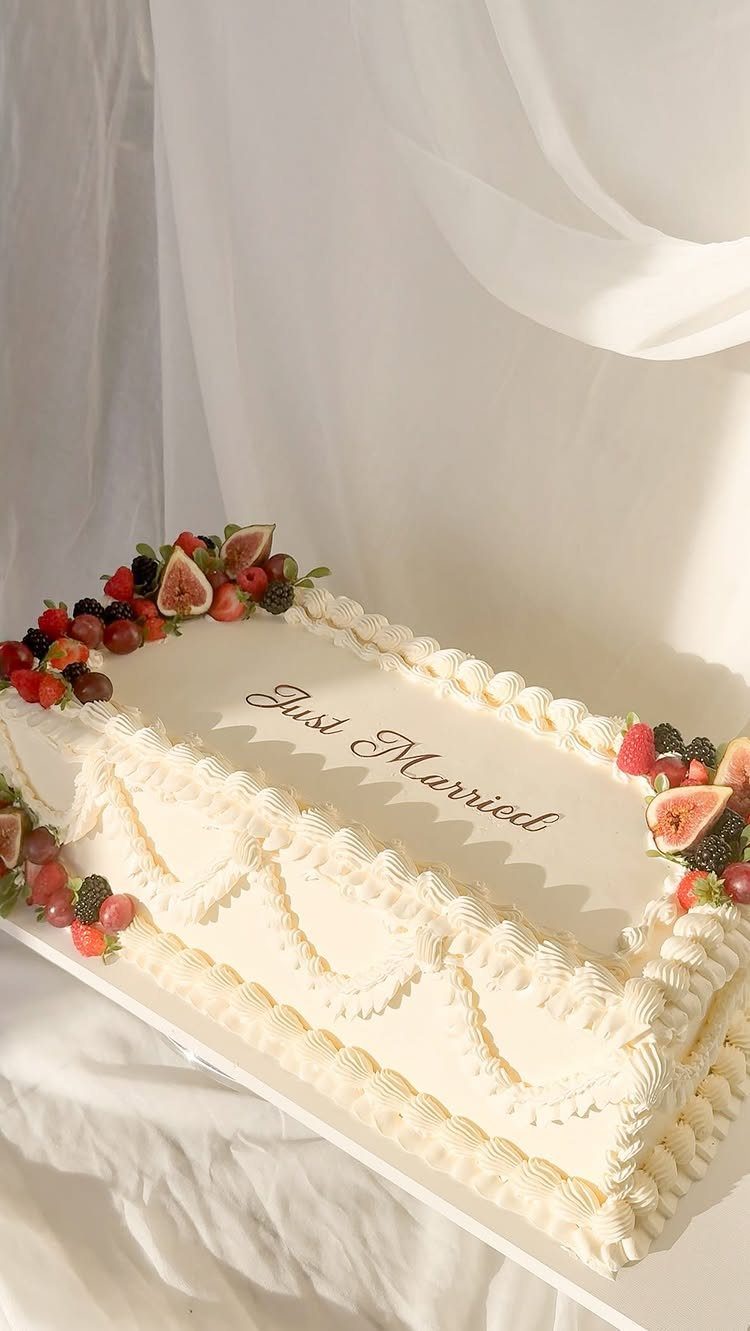 White wedding cake topped with fresh figs and berries with Just Married text