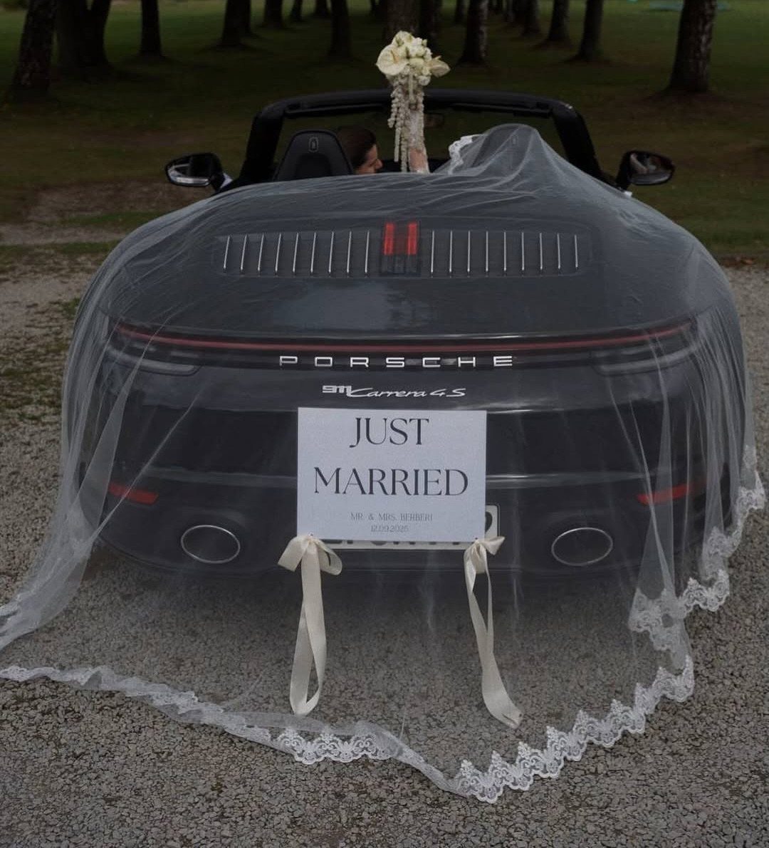 Dark grey Porsche convertible decorated with a lace veil and Just Married sign.