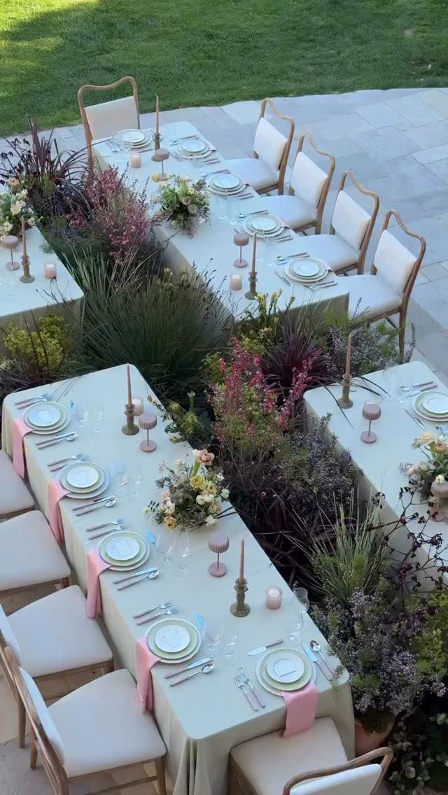 Outdoor wedding tables with cream linens, pink napkins, and lush floral arrangements.