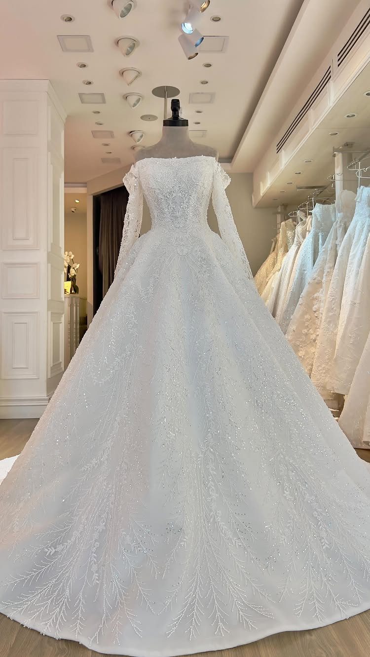White sparkling ballgown wedding dress with long sleeves on a bridal shop mannequin
