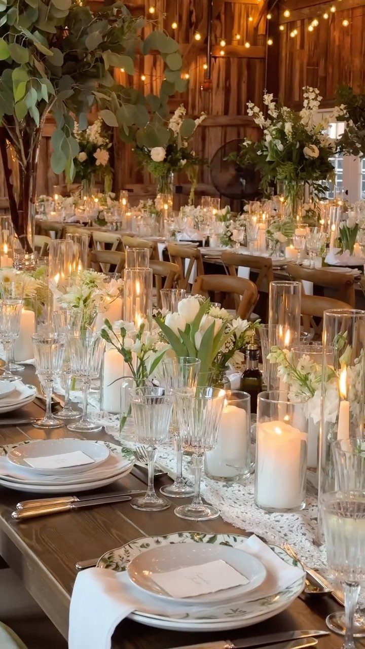 Wooden wedding table with white flowers and candles inside a rustic wooden barn