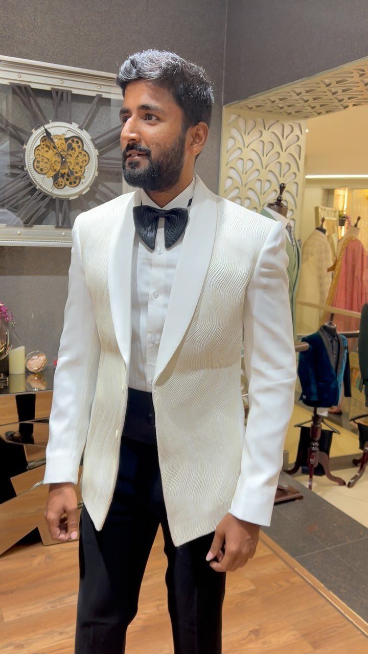 Man wearing a white textured tuxedo jacket with a black bow tie and trousers.