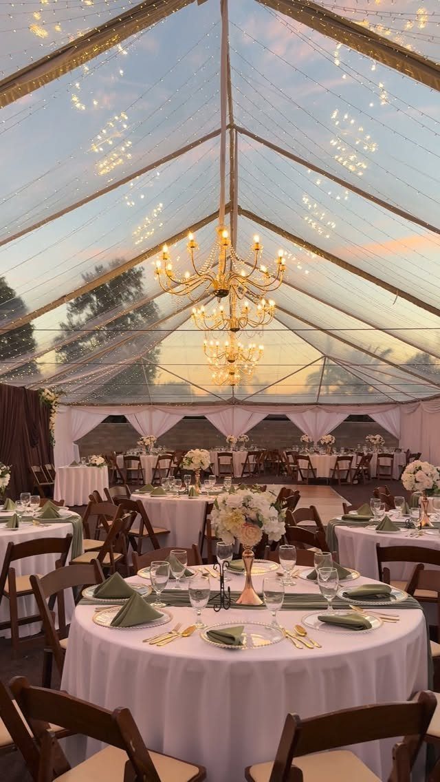 Wedding reception in a clear tent with twinkle lights and gold chandeliers.