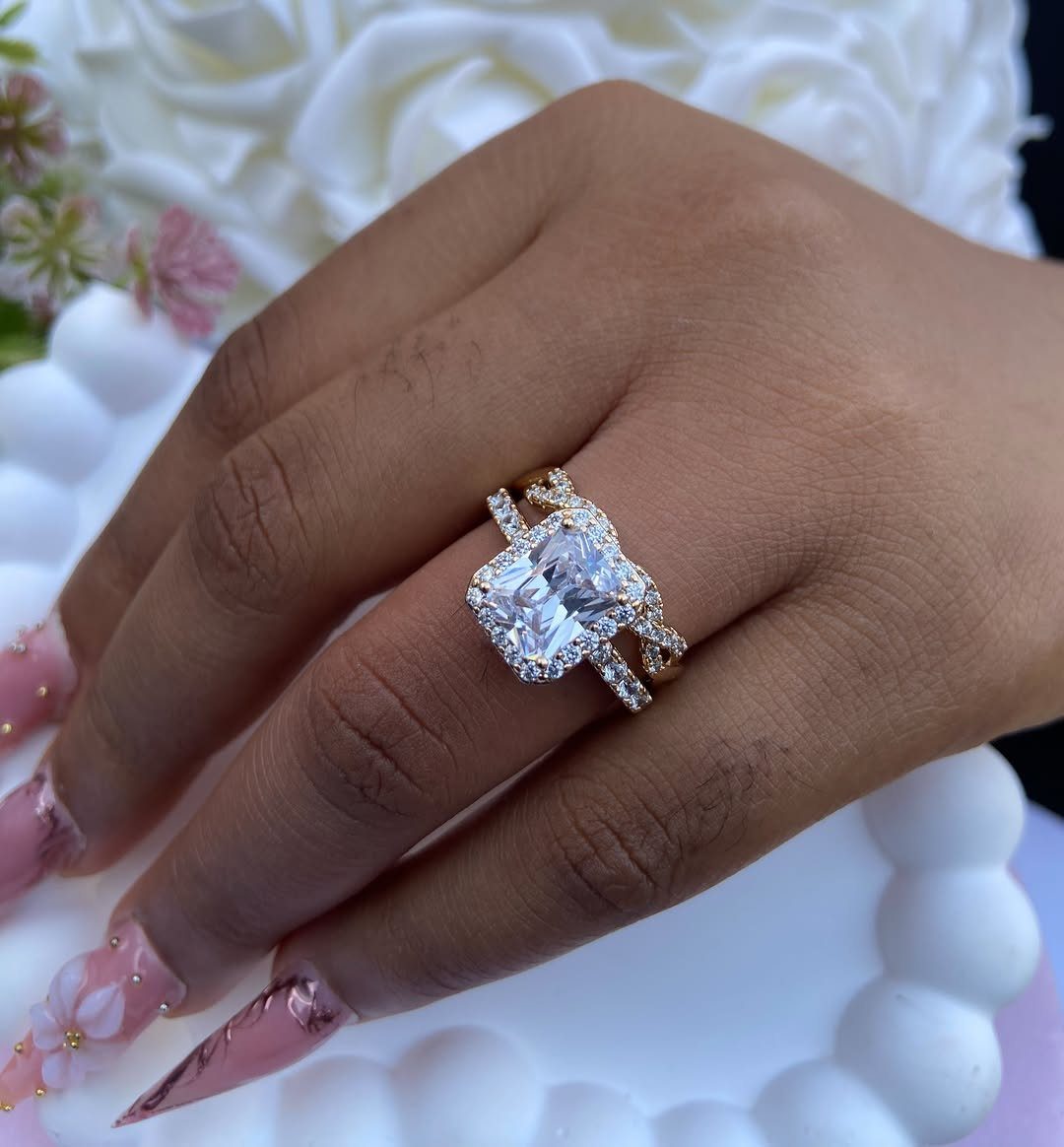 Rose gold diamond engagement ring on a finger against white rose background