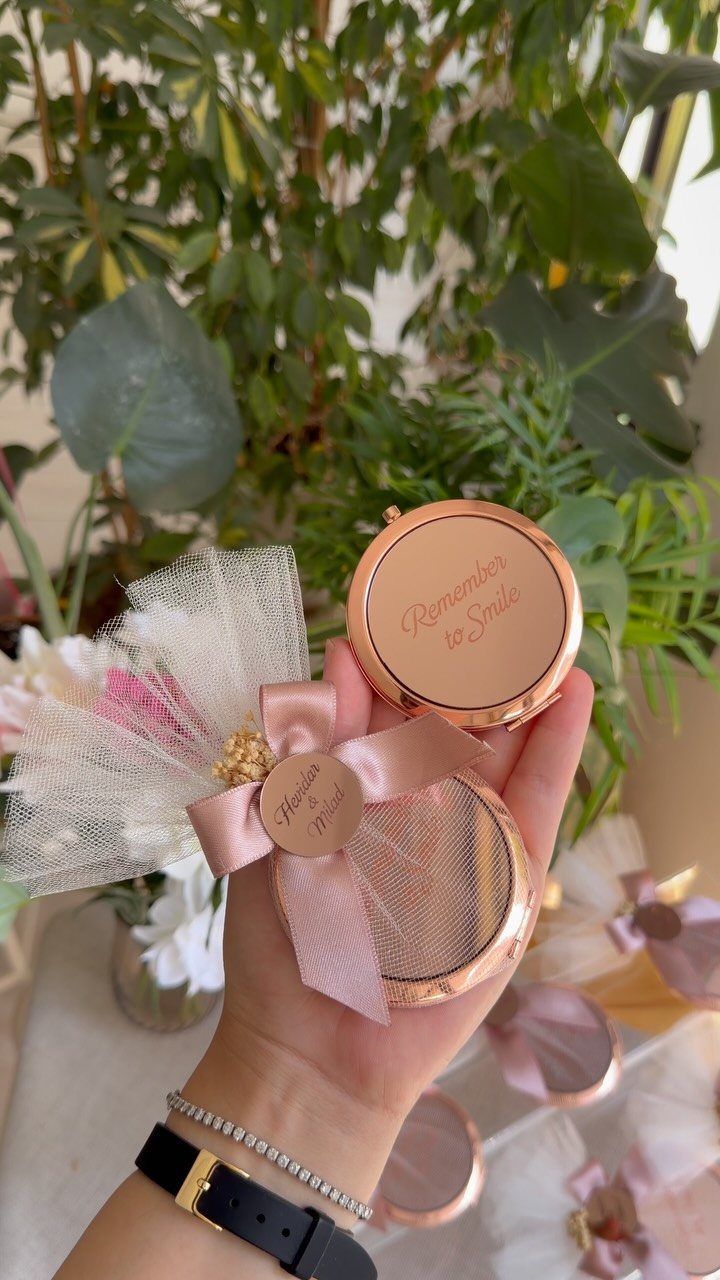 Rose gold compact mirror wedding favors with pink bows and white tulle accents.
