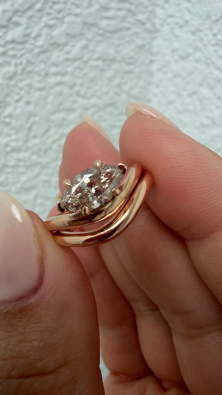 Rose gold wedding ring set with a marquise diamond held by fingers