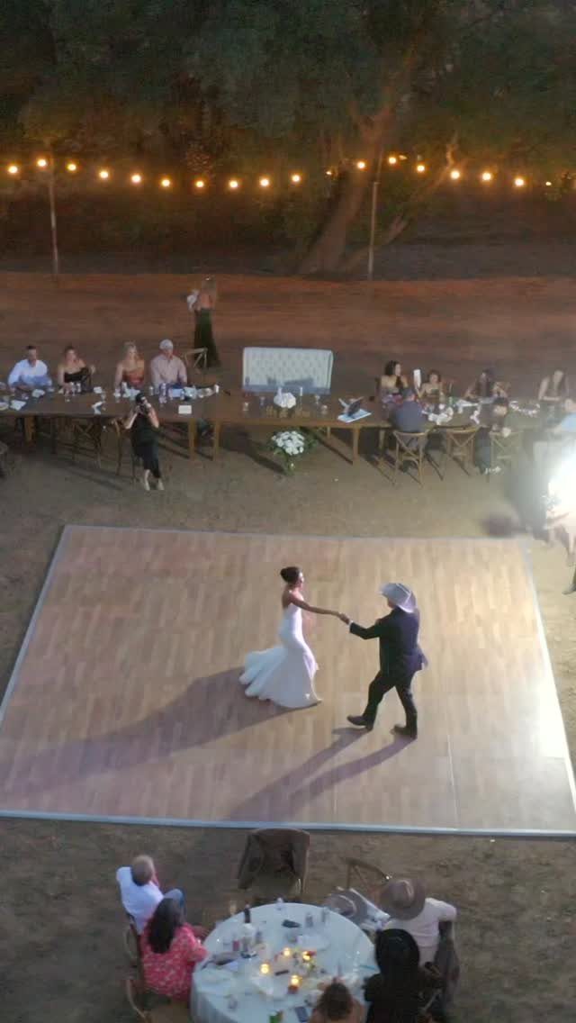 Bride and groom dancing on a wooden dance floor at a rustic outdoor reception