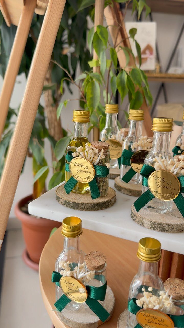 Small oil bottles with green ribbons and gold tags on wooden slices.
