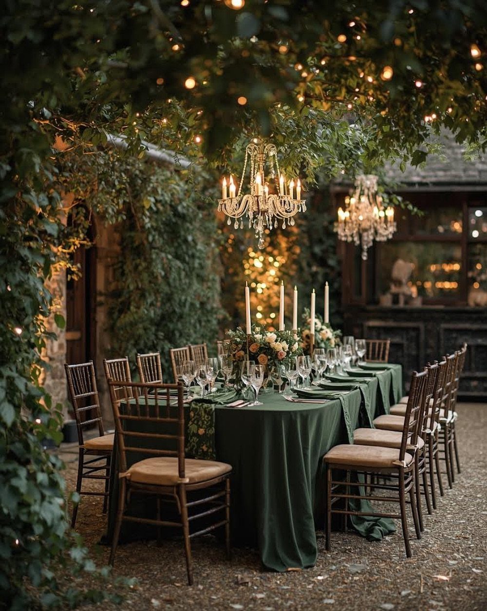 Long dining table with green linens under a canopy of lush green foliage