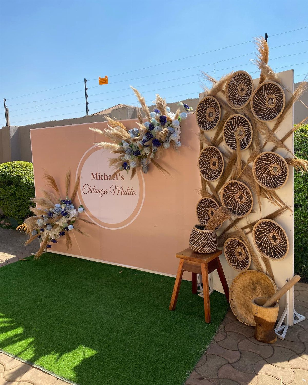 Peach backdrop with floral arrangements and woven baskets for a rustic photo booth.