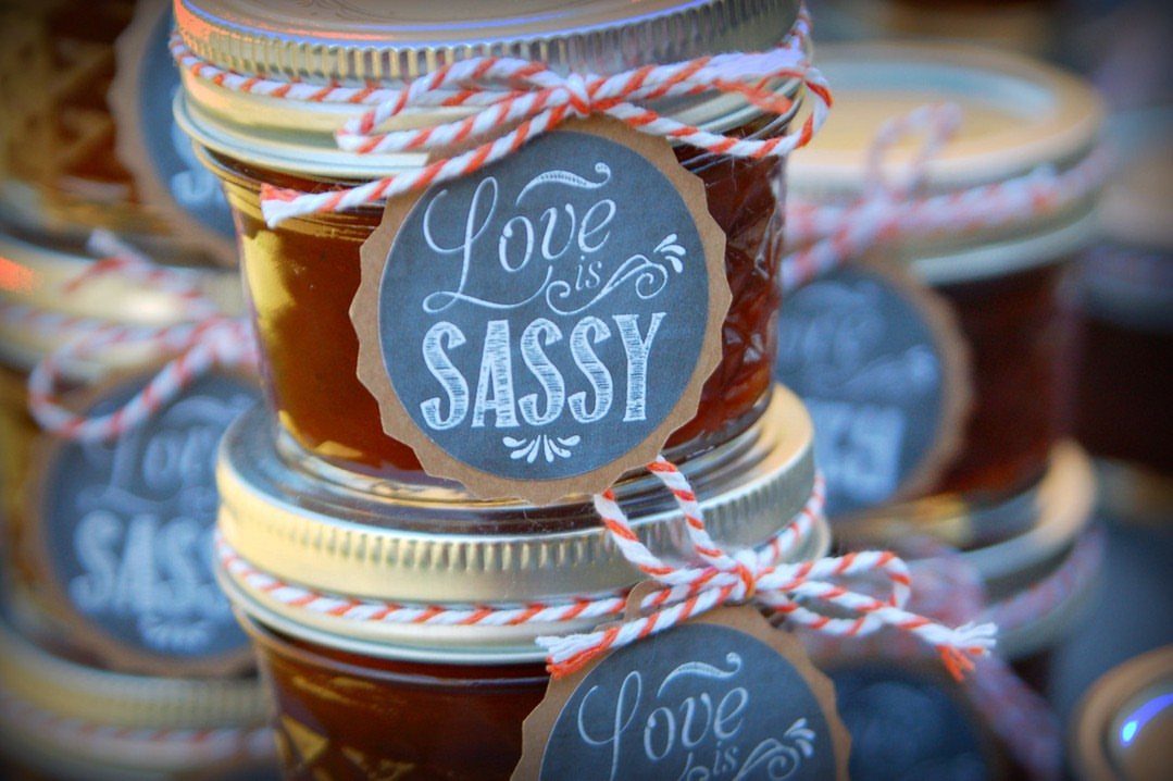 Glass jam jars with gold lids and chalkboard labels saying Love is Sassy