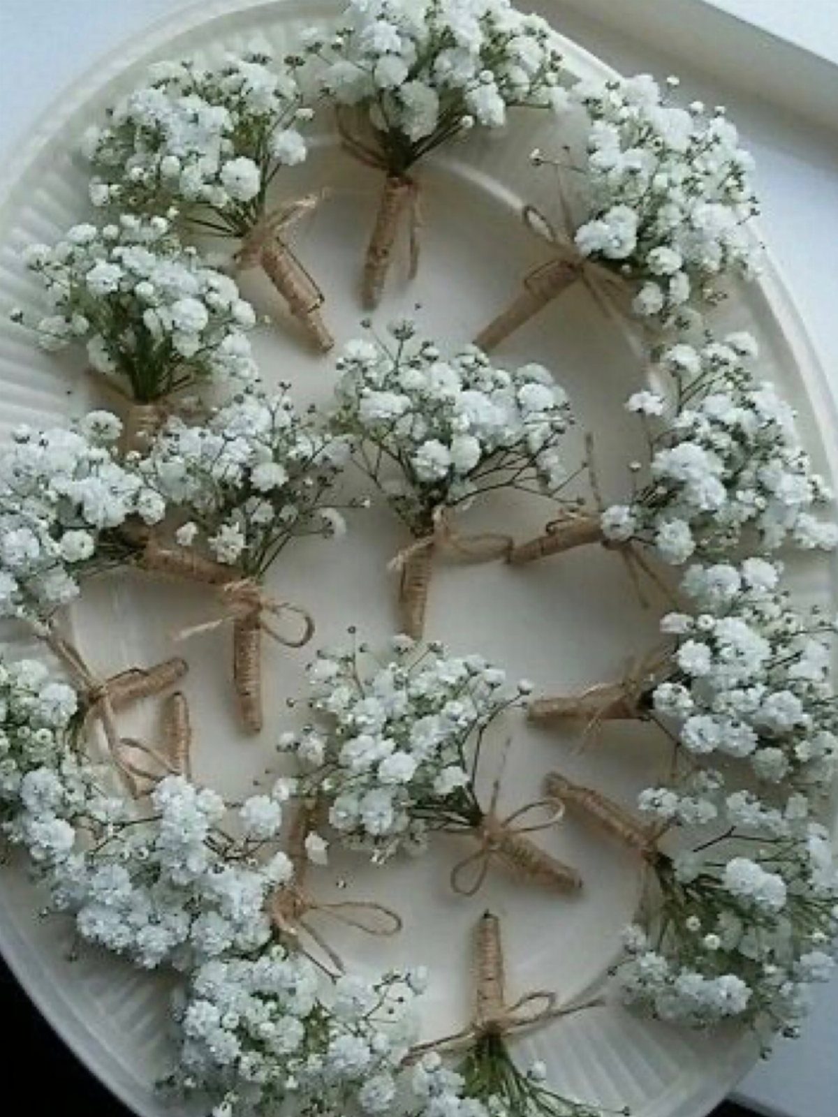 Small baby's breath flower bouquets with twine wraps on a white platter.
