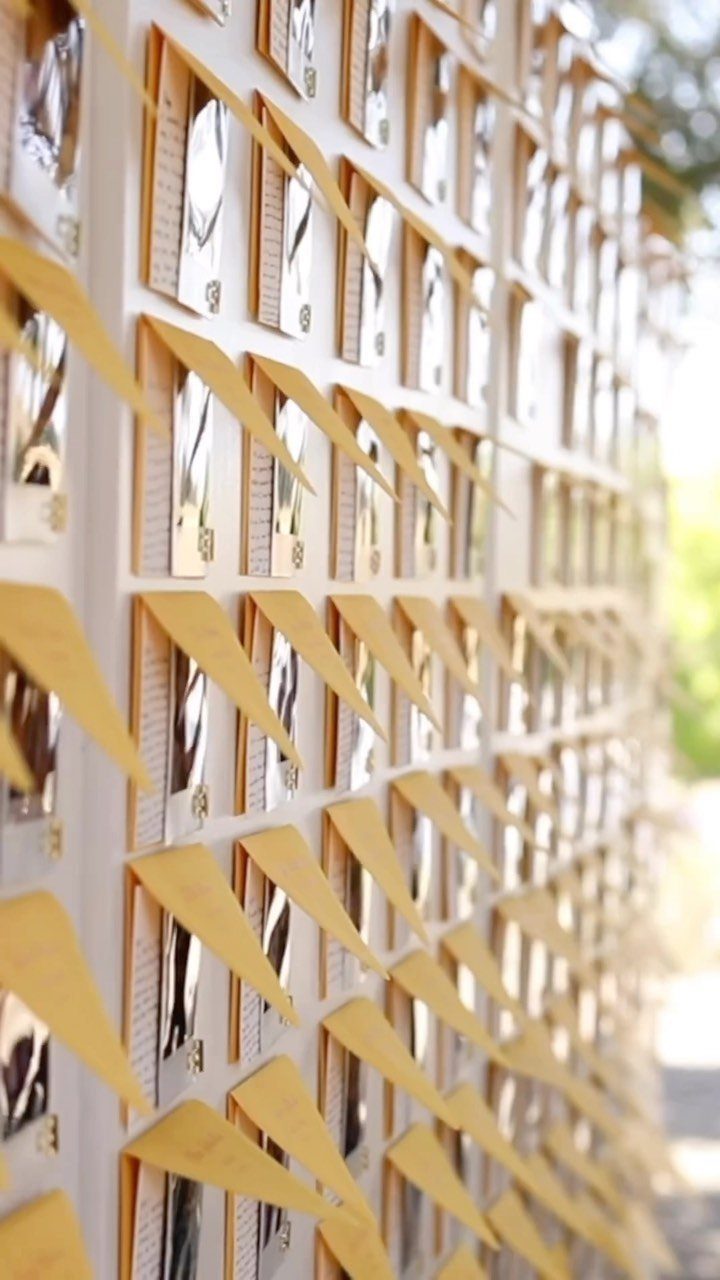 White wall with yellow pockets holding guest name cards and small photos