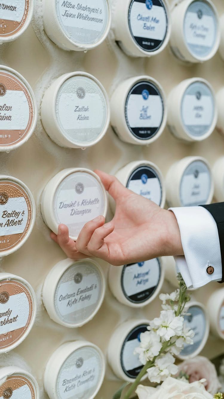 Cheese wheel wall with name labels and a hand reaching for a card.