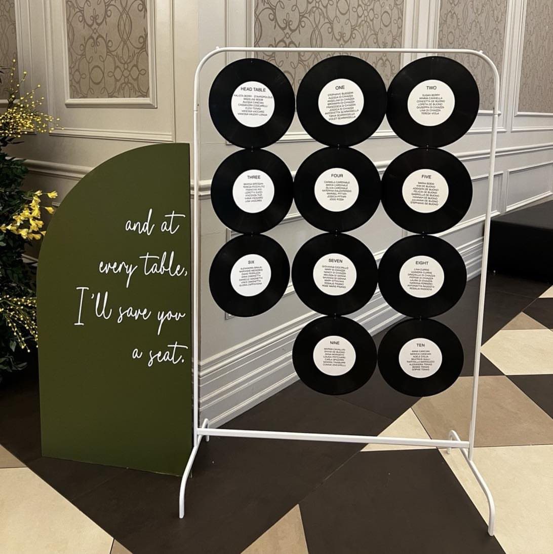 Vinyl records on a white metal rack serving as a wedding seating chart.