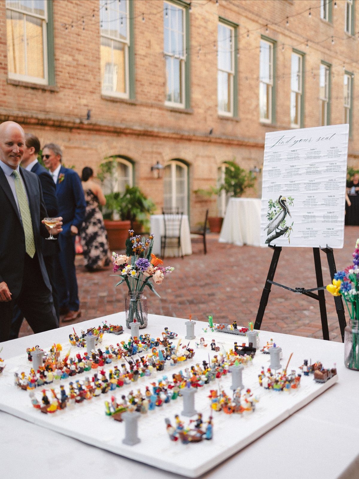LEGO figure seating arrangement on a white table next to a wedding chart.