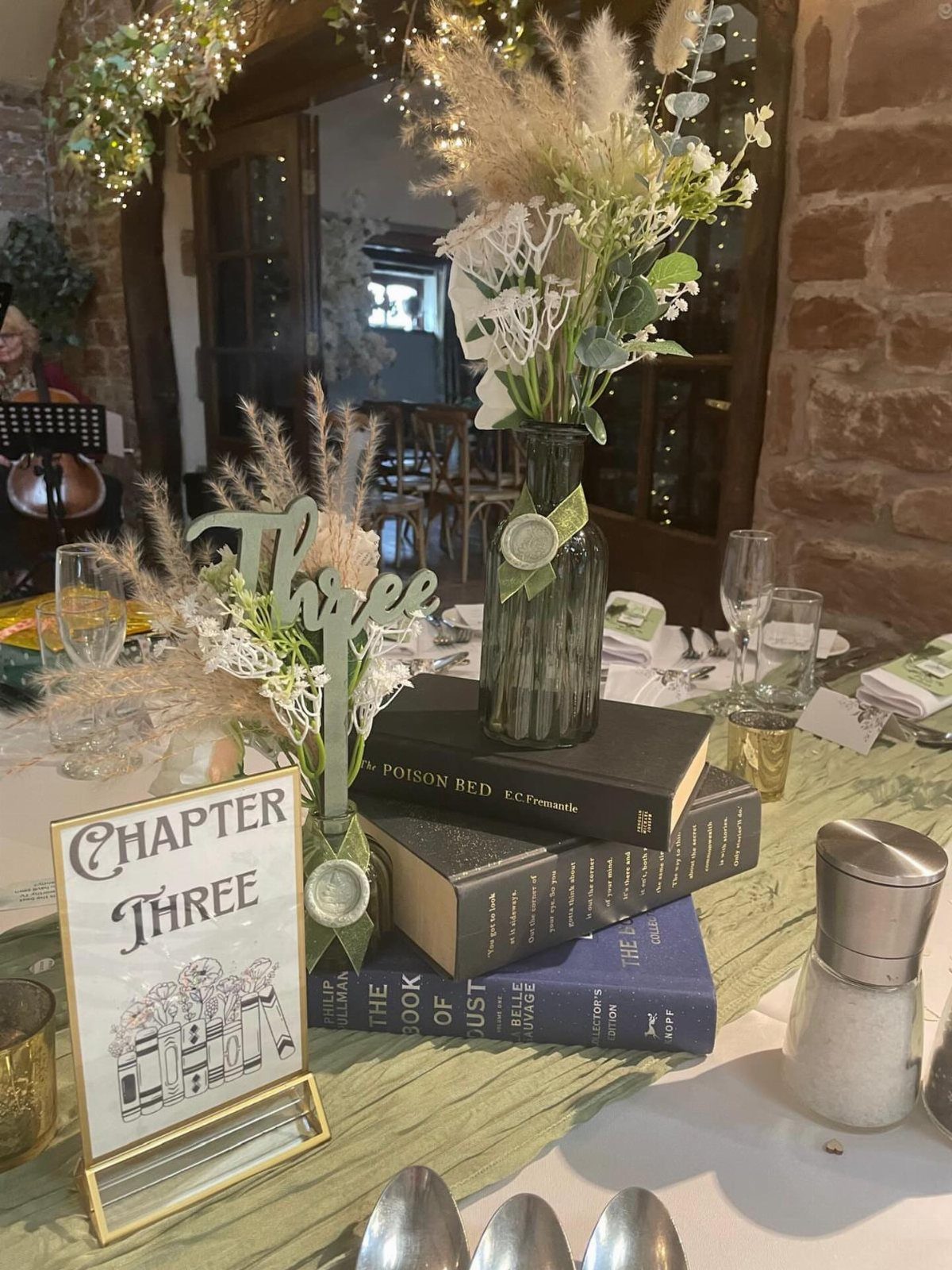 Stacked vintage books topped with a floral vase and a Chapter Three sign.