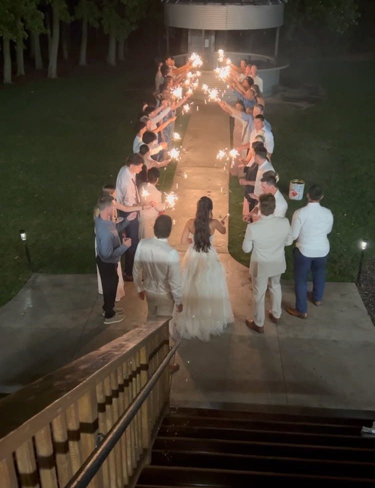 Bride and groom walking through a sparkler send-off line of wedding guests at night