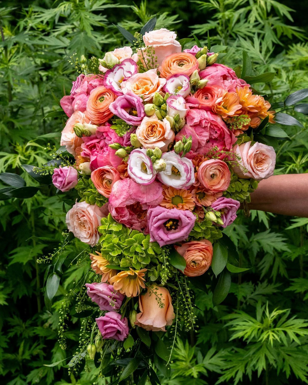 Cascading wedding bouquet with pink and peach roses and green hydrangea blooms.