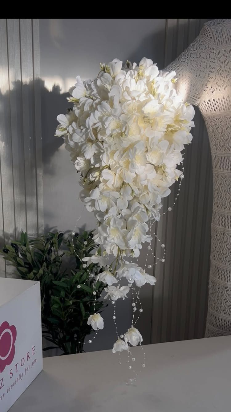 Cascading white bridal bouquet with pearls against a grey ribbed wall background