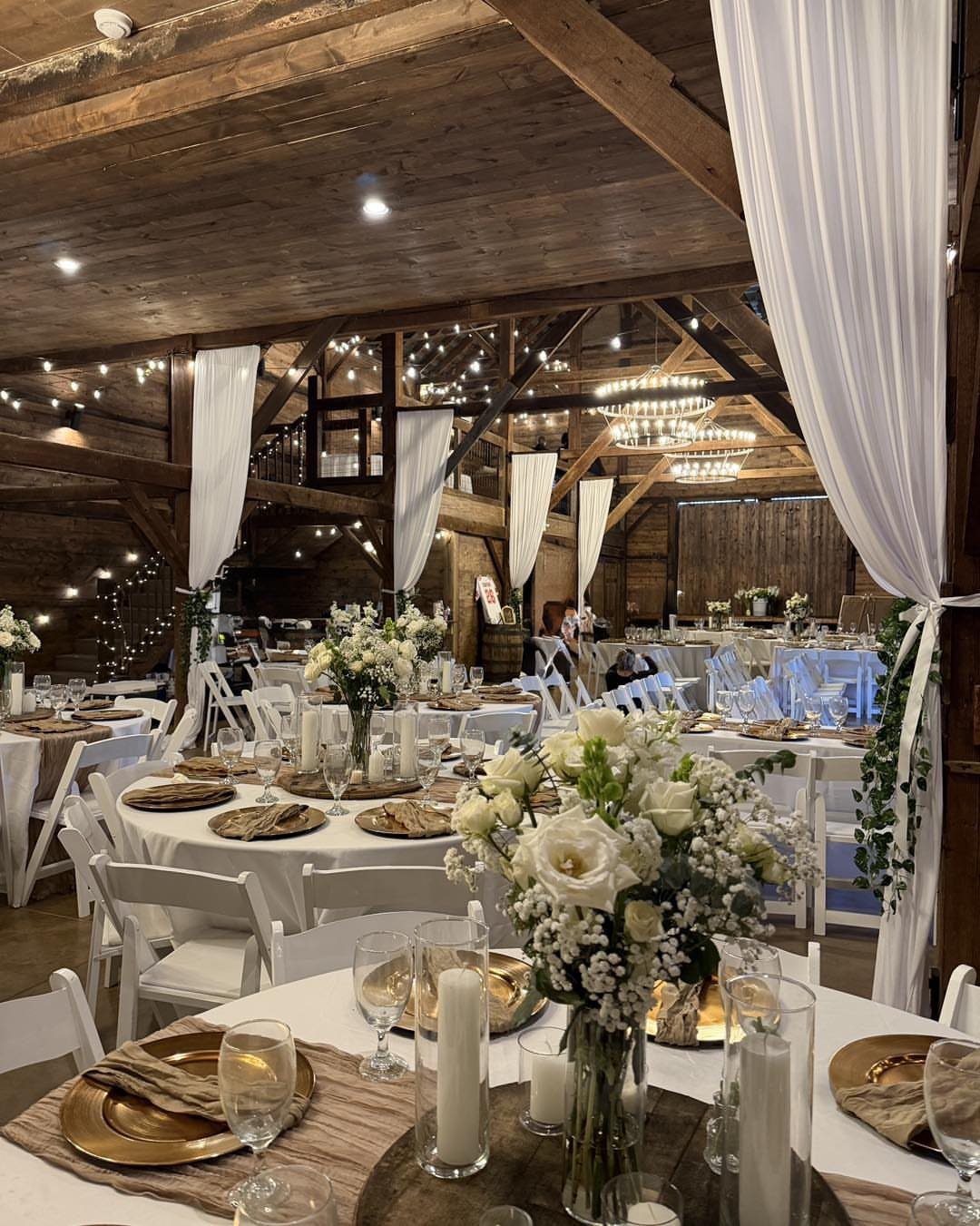 Rustic barn wedding reception with burlap table runners and white floral centerpieces.