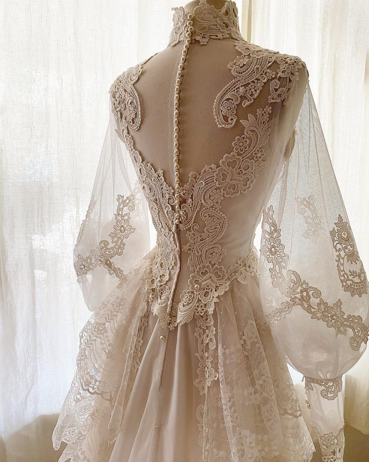 Ivory vintage wedding dress with lace embroidery and puff sleeves on a mannequin