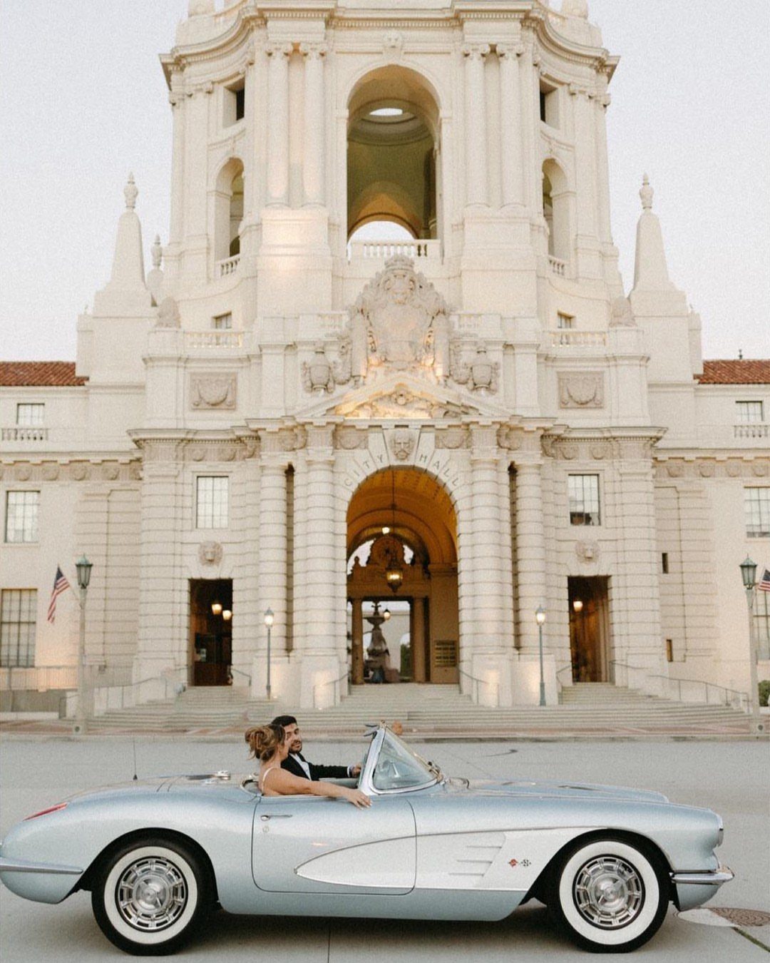 Couple in wedding attire sitting in a light blue vintage convertible car