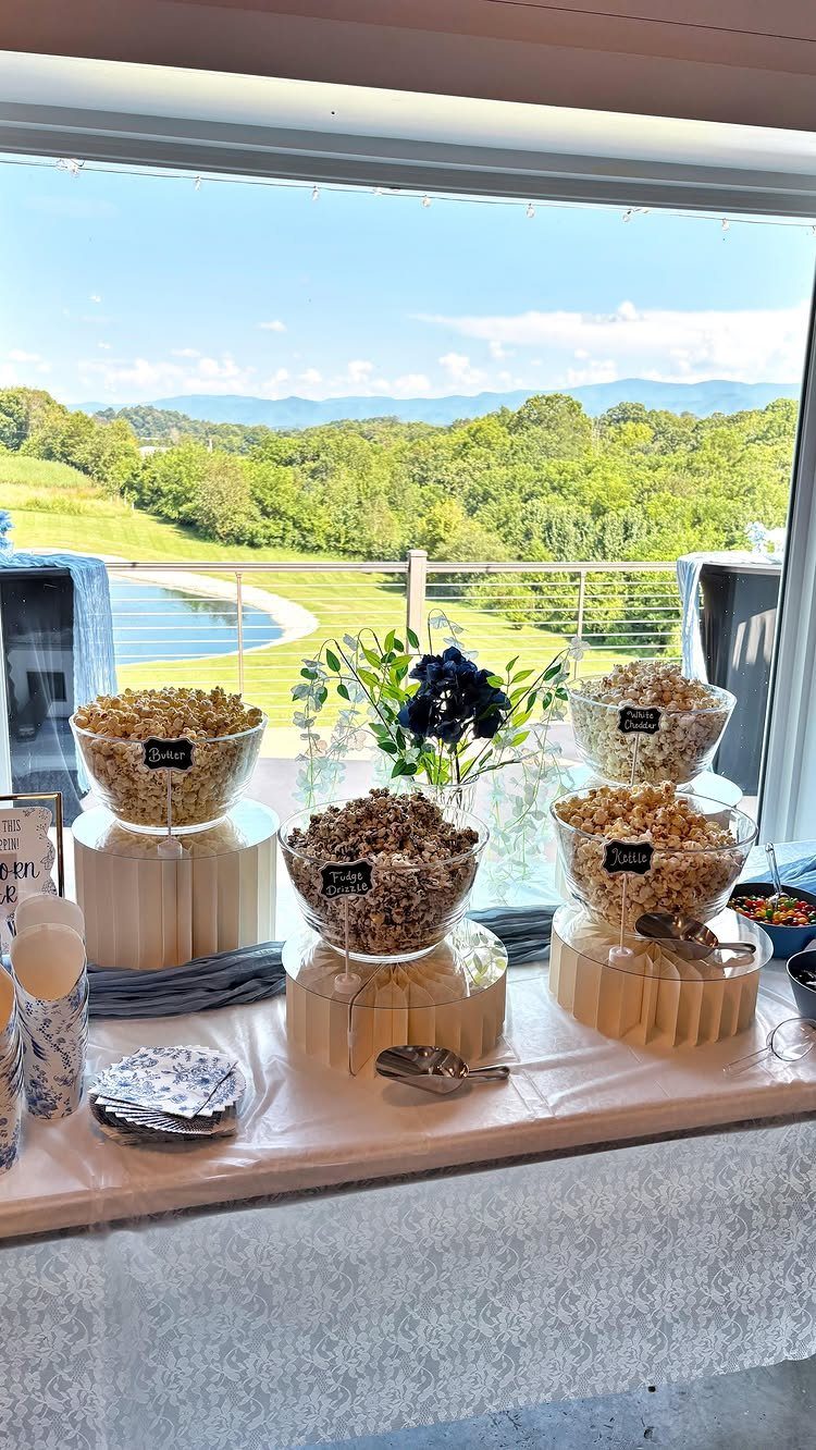 Popcorn station with various flavors in glass bowls overlooking a scenic mountain landscape.