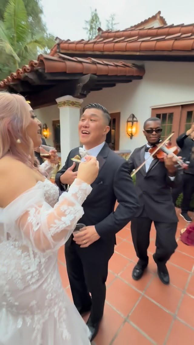 Bride and groom talking on a patio with a violinist playing in background