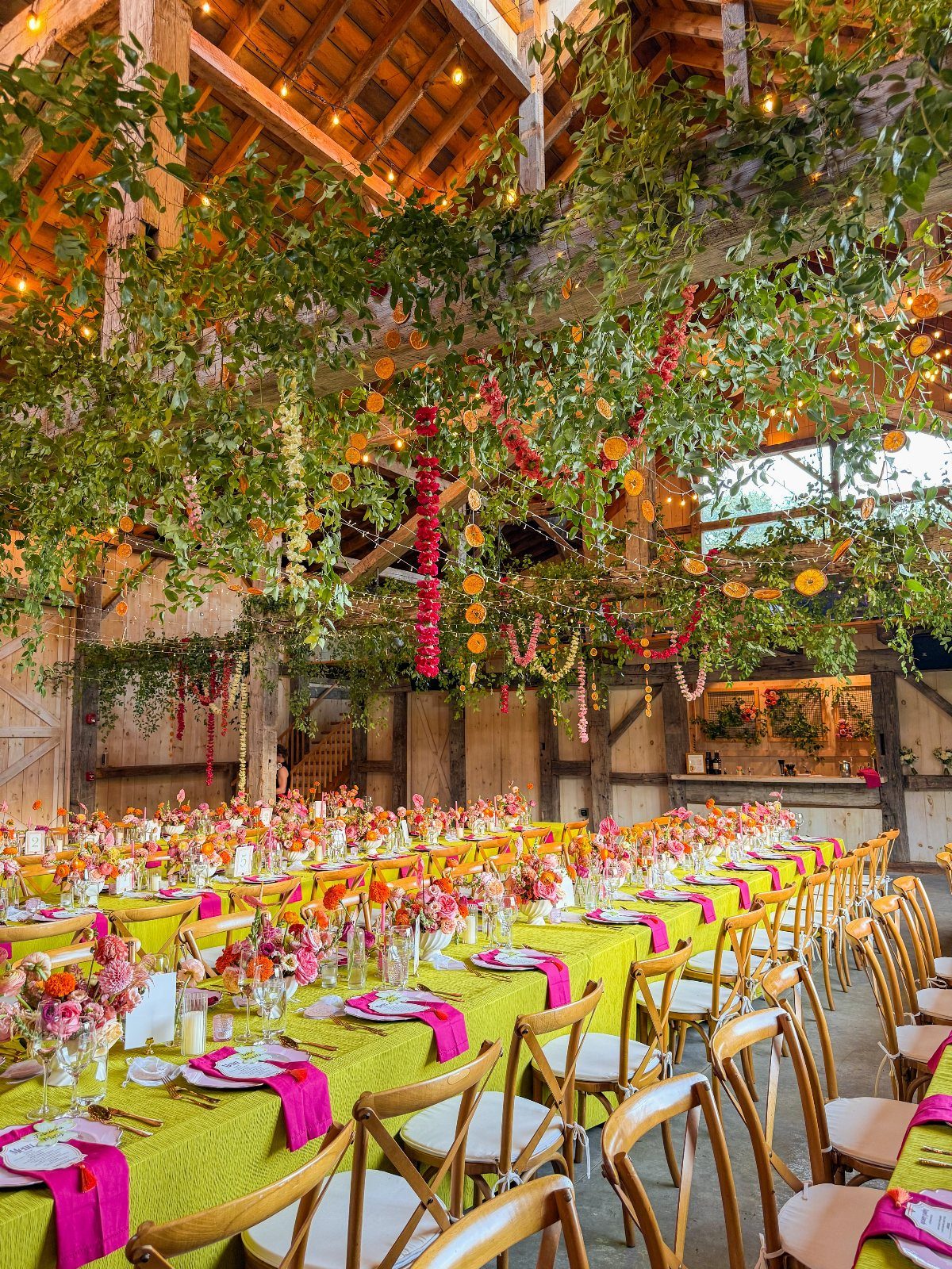 Rustic barn wedding reception with lime green linens and orange floral ceiling installations