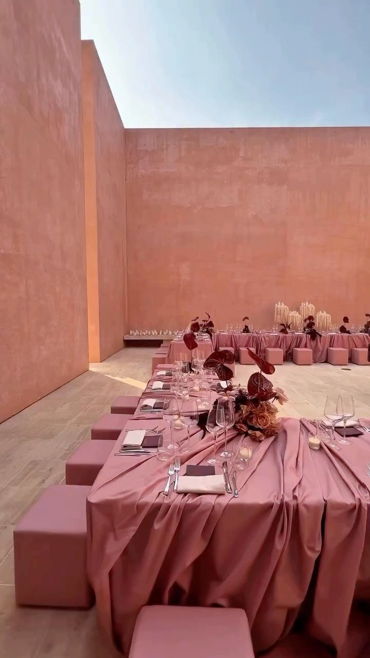 Dusty pink table setting with matching cubic seats against textured pink walls.