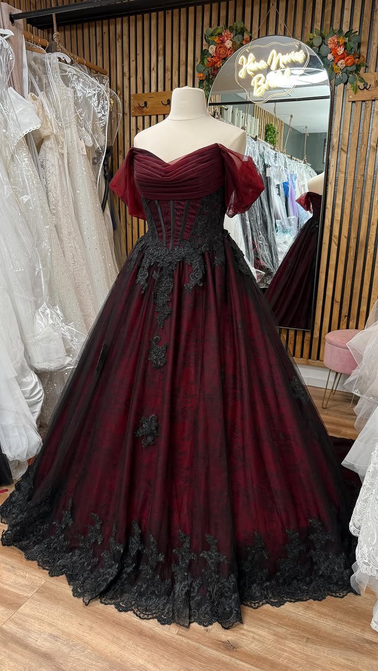 Burgundy ball gown with black lace detailing displayed on a white mannequin.