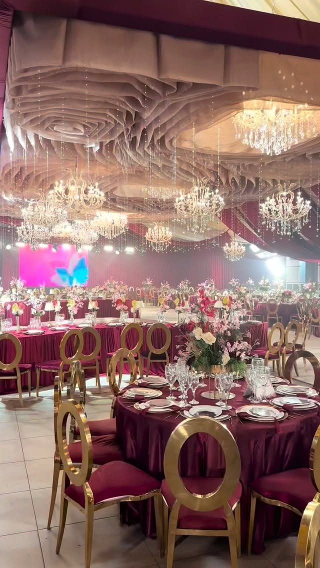 Maroon banquet tables with gold chairs and burgundy and blush floral centerpieces.