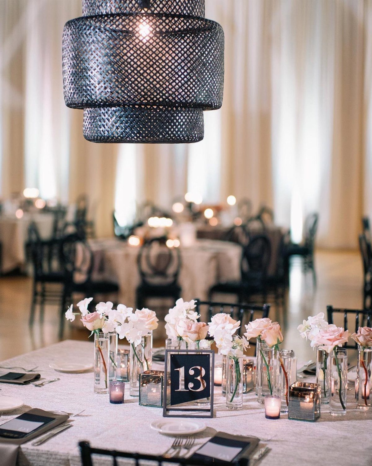 Wedding table setting with white flowers, black accents, and a grey pendant light.
