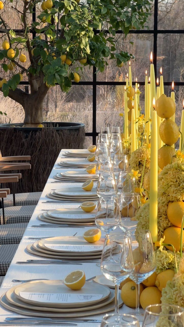 Dining table decorated with yellow candles, fresh lemons, and yellow floral arrangements.
