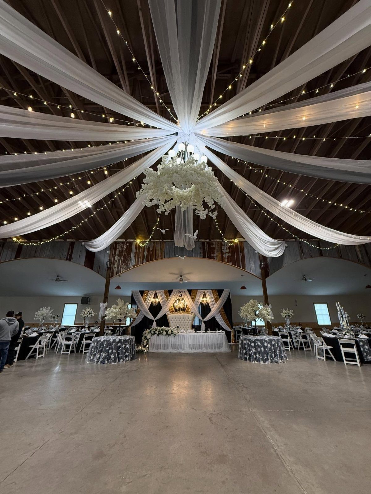White fabric draping and fairy lights on a ceiling above wedding reception tables