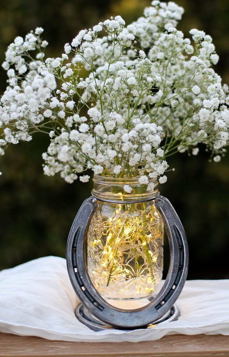 Mason jar centerpiece with baby's breath flowers and glowing fairy lights in horseshoe