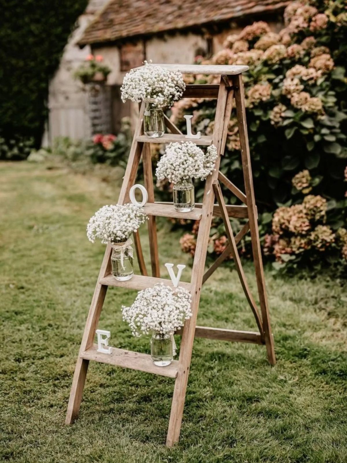 Wooden ladder decorated with white baby's breath flowers and LOVE block letters outdoors