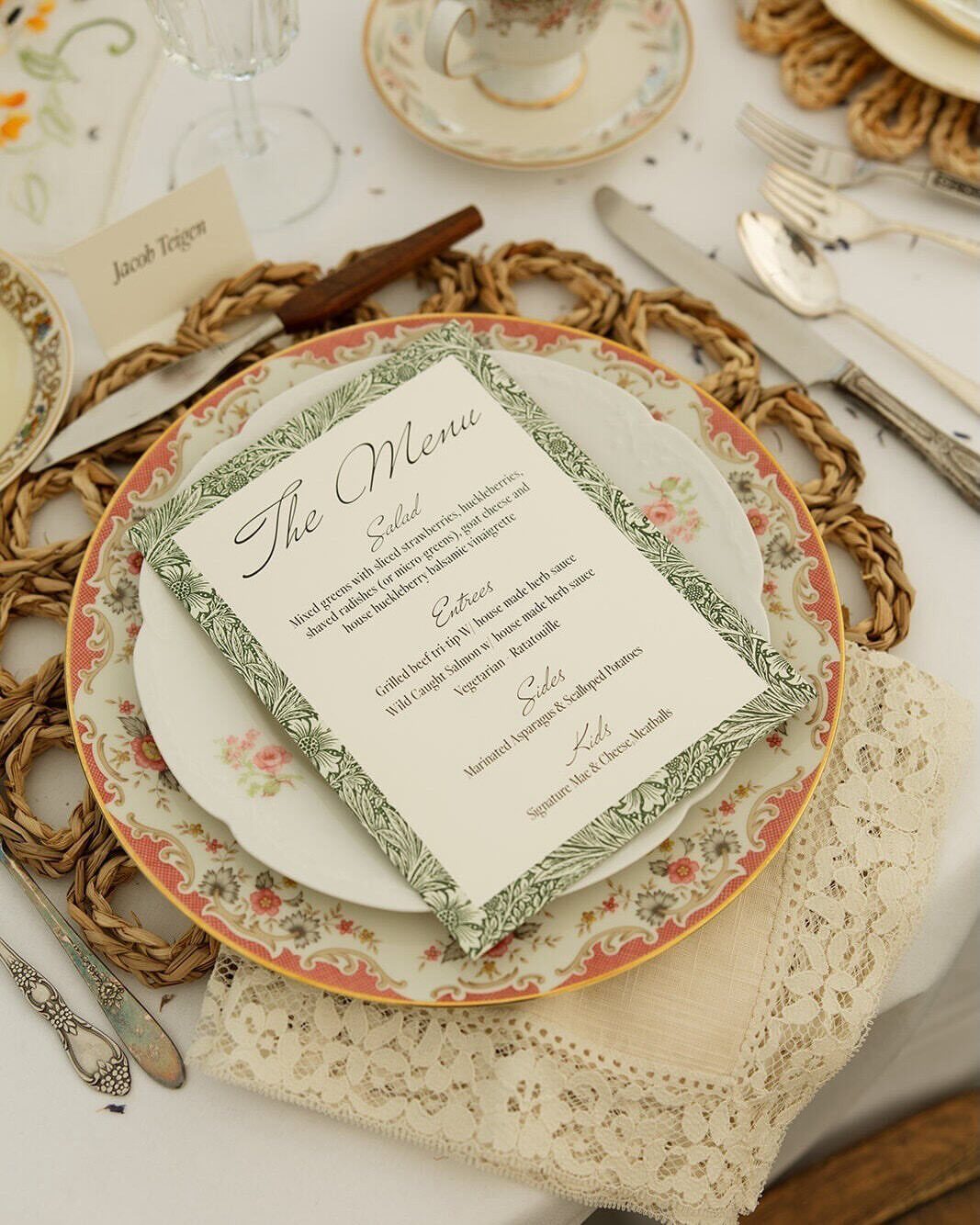 Floral vintage plate with a printed menu and silver cutlery on a table