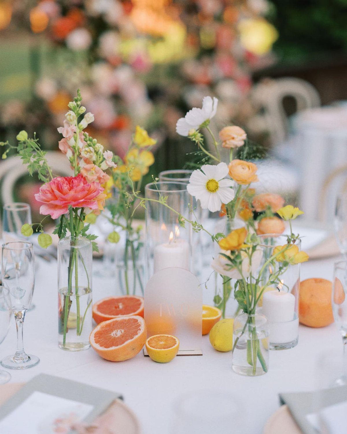 Citrus fruit slices and colorful flowers arranged as a centerpiece on a white table.